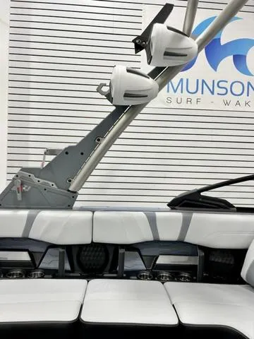 Slide: The Image of 2024 Malibu 23 MXZ boat interior with speakers and seating, Munson Surf & Wake logo in background. - 15