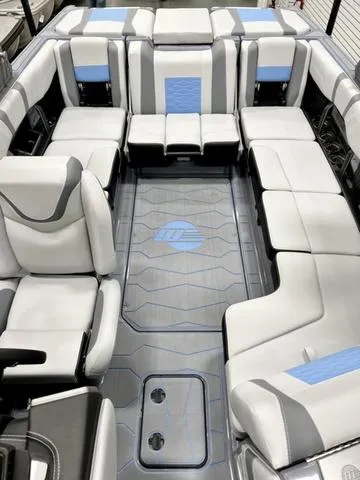 Slide: The Image of 2024 Malibu 23 MXZ boat interior with white and blue seating, modern design. - 9