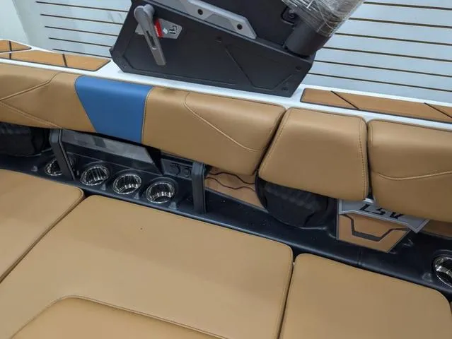 Slide: The Image of 2025 Malibu 23 LSV boat interior with tan and blue seating, cup holders, and sleek design. - 10