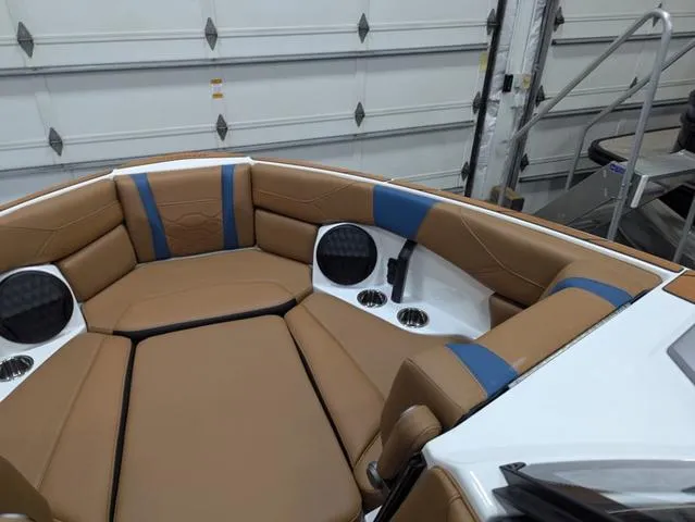 Slide: The Image of 2025 Malibu 23 LSV boat interior with tan and blue seating, cup holders, and speakers. - 18