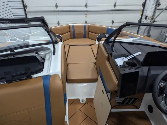Slide: The Image of 2025 Malibu 23 LSV boat interior with tan and blue seating, modern dashboard, and open bow design. - 6
