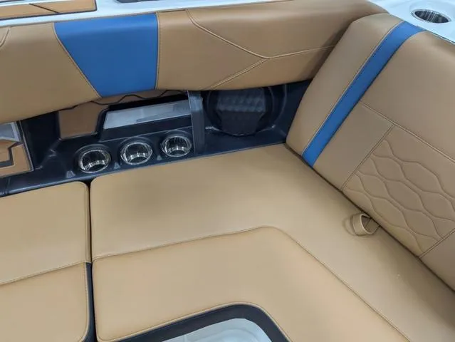 Slide: The Image of 2025 Malibu 23 LSV boat interior with tan and blue upholstery, featuring cup holders. - 9