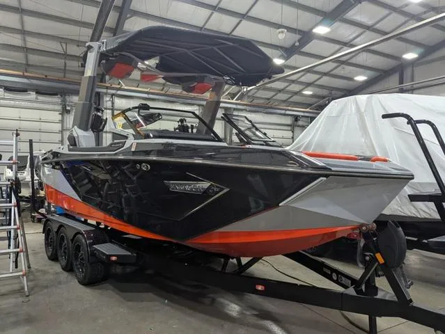 Slide: The Image of 2020 Nautique G23 Paragon boat in a warehouse, black and orange design, on a trailer. - 1
