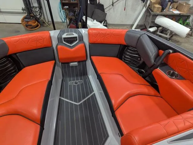 Slide: The Image of 2020 Nautique G23 Paragon boat interior with red and gray seating in a workshop. - 12