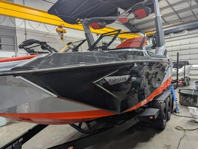 Slide: The Image of 2020 Nautique G23 Paragon boat in a garage, featuring sleek black and orange design. - 20