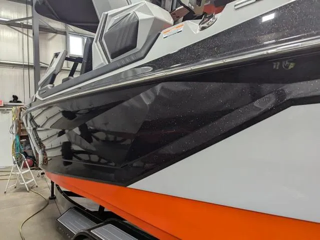 Slide: The Image of 2020 Nautique G23 Paragon boat with sleek black and orange design in a garage. - 36
