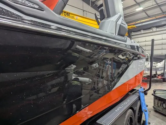 Slide: The Image of 2020 Nautique G23 Paragon boat in a garage, showcasing sleek black and orange design. - 4
