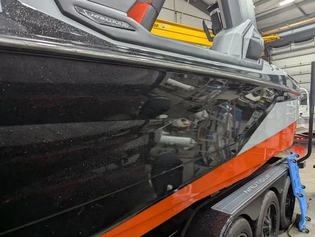 Slide: The Image of 2020 Nautique G23 Paragon boat in a garage, showcasing sleek black and orange design. - 6