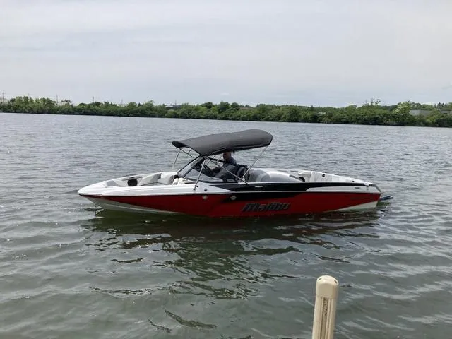 Slide: The Image of 2024 Malibu TXi Mo boat on calm water with canopy. - 10