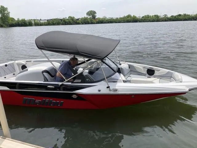 Slide: The Image of 2024 Malibu TXi Mo boat with canopy on a calm lake. - 3