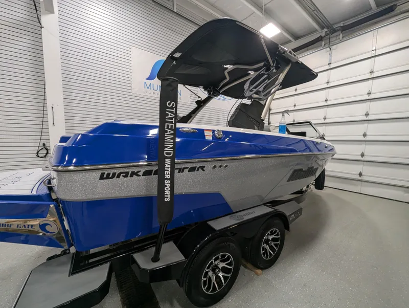Slide: The Image of 2021 Malibu Wakesetter 20 VTX boat in showroom, blue and silver design, on trailer. - 2