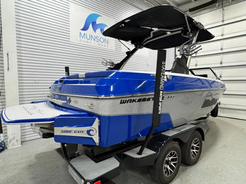 Slide: The Image of 2021 Malibu Wakesetter 20 VTX boat in showroom, blue and silver design, on trailer. - 3