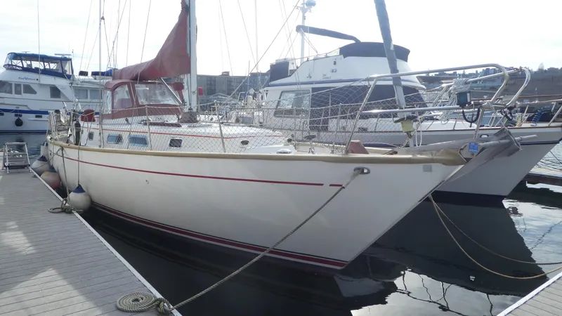 The Image of 1990 Celestial 48 Center Cockpit sailboat docked at marina, featuring red sail cover. - 0
