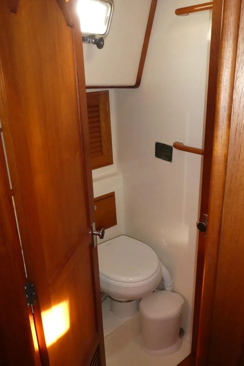 Slide: The Image of 1990 Celestial 48 Center Cockpit bathroom with wooden door and compact toilet. - 29