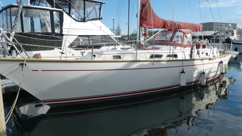 Slide: The Image of 1990 Celestial 48 Center Cockpit sailboat docked in marina, featuring red accents and protective netting. - 3
