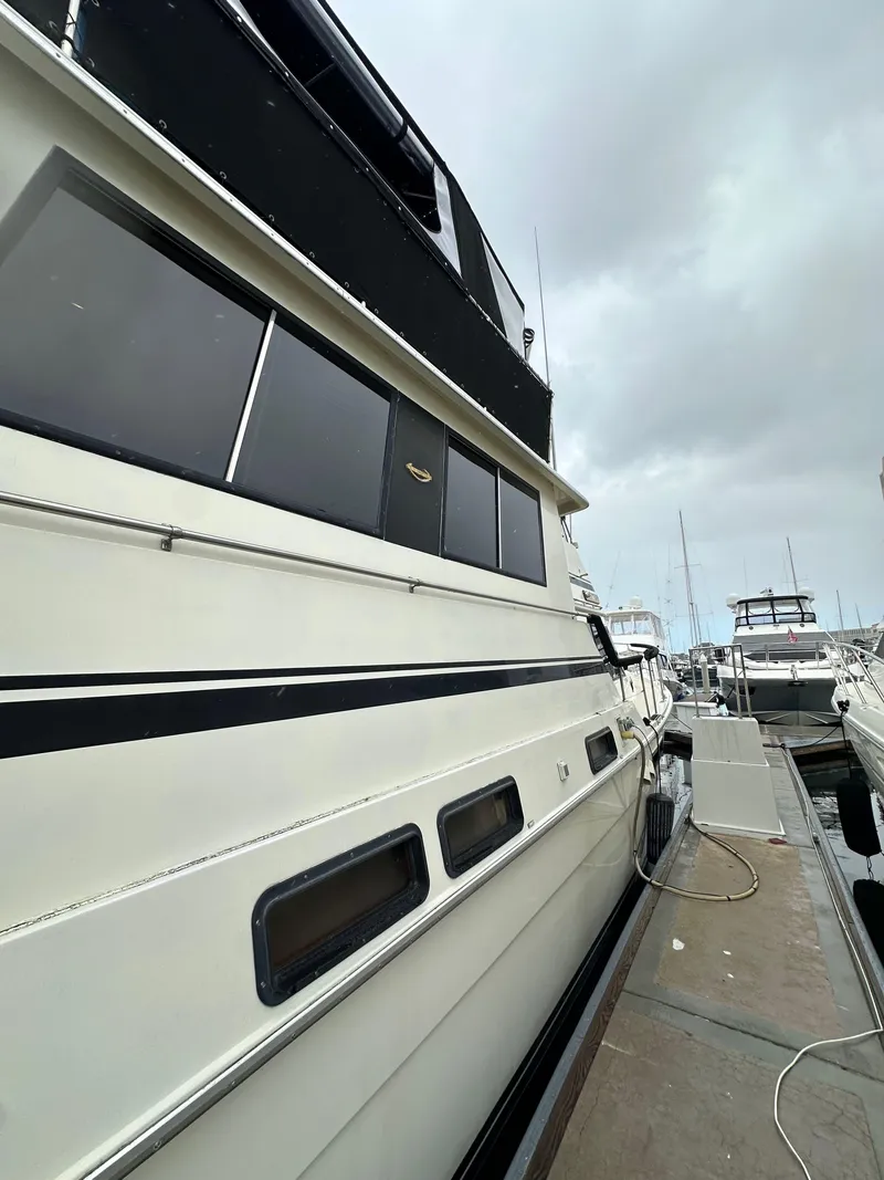 Slide: The Image of 1985 Gulfstar 49 Motor Yacht docked, showcasing sleek design and windows. - 14