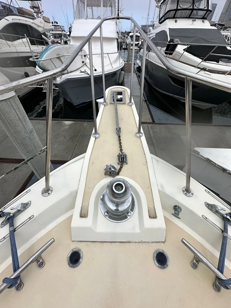 Slide: The Image of 1985 Gulfstar 49 Motor Yacht bow view at marina, showcasing anchor and railing. - 19