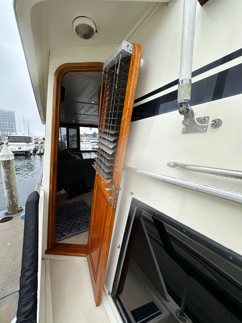Slide: The Image of 1985 Gulfstar 49 Motor Yacht side entrance with open wooden door, docked at marina. - 23