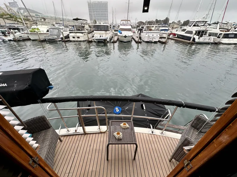 Slide: The Image of 1985 Gulfstar 49 Motor Yacht docked, featuring a cozy deck with chairs and a table. - 31