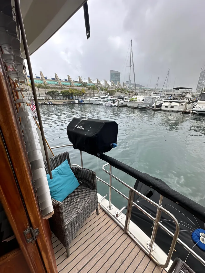 Slide: The Image of 1985 Gulfstar 49 Motor Yacht docked, featuring a cozy deck with a chair and grill. - 32
