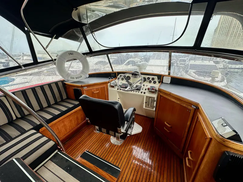 Slide: The Image of 1985 Gulfstar 49 Motor Yacht helm with striped seating, wooden flooring, and navigation controls. - 41