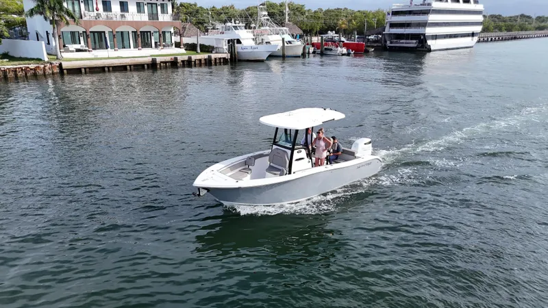 The Image of 2023 Sea Pro 239 Deluxe CC boat cruising in a marina with waterfront buildings. - 0
