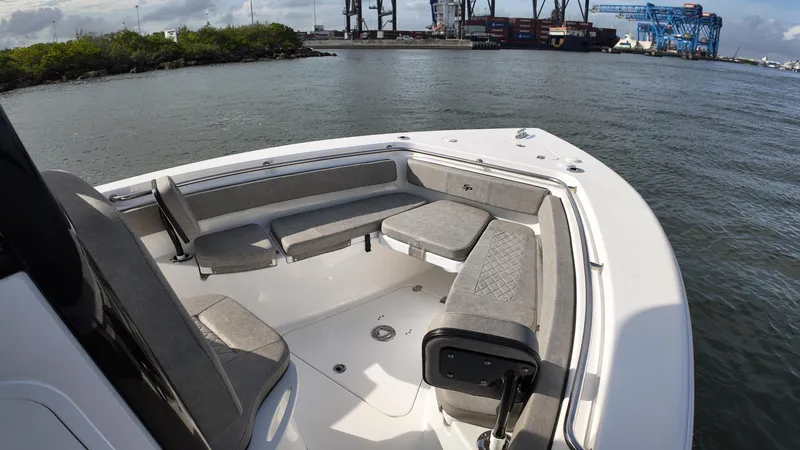 Slide: The Image of 2023 Sea Pro 239 Deluxe CC boat interior with cushioned seating, dockside view. - 18