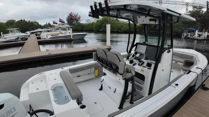 Slide: The Image of 2023 Sea Pro 239 Deluxe CC boat docked, featuring spacious seating and modern controls. - 23