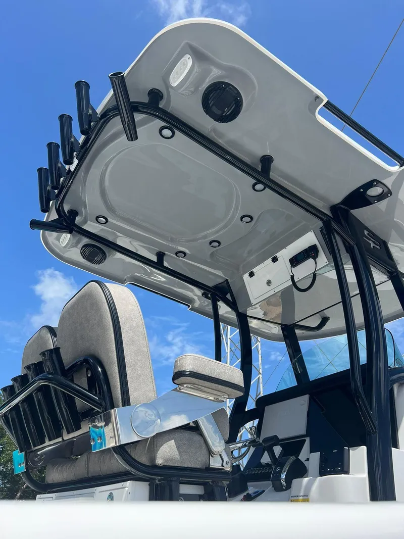 Slide: The Image of 2023 Sea Pro 239 Deluxe CC boat interior with seating and rod holders under a clear blue sky. - 33