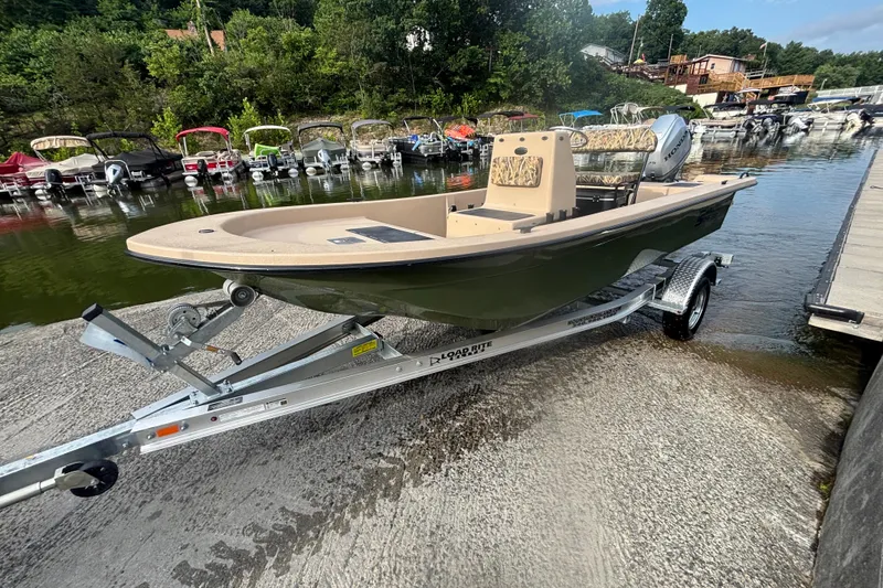 The Image of 2025 Carolina Skiff E18 JVX CC boat on trailer by a lakeside dock. - 0