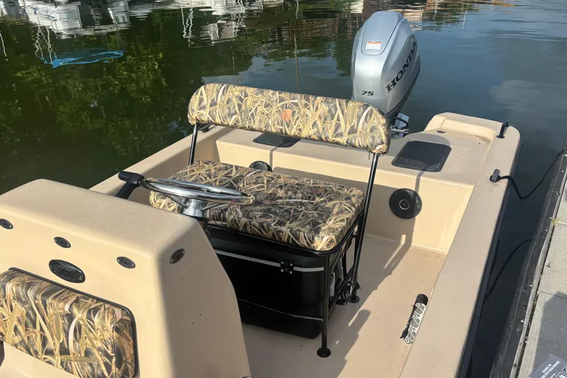 Slide: The Image of 2025 Carolina Skiff E18 JVX CC boat with camouflage seating and Honda outboard motor. - 12