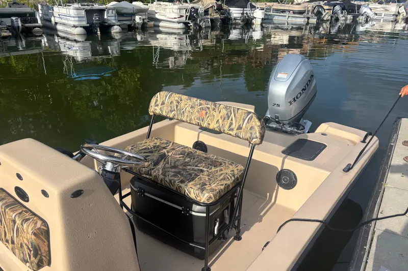 Slide: The Image of 2025 Carolina Skiff E18 JVX CC boat with Honda outboard motor docked at marina. - 13