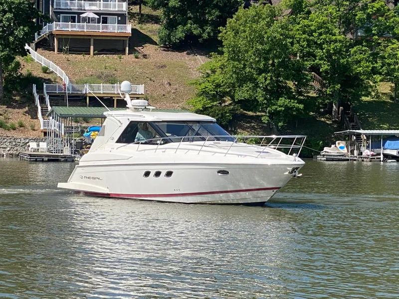 Slide: The Image of 2012 Regal 42 Sport Coupe cruising on a serene lake near waterfront homes. - 2