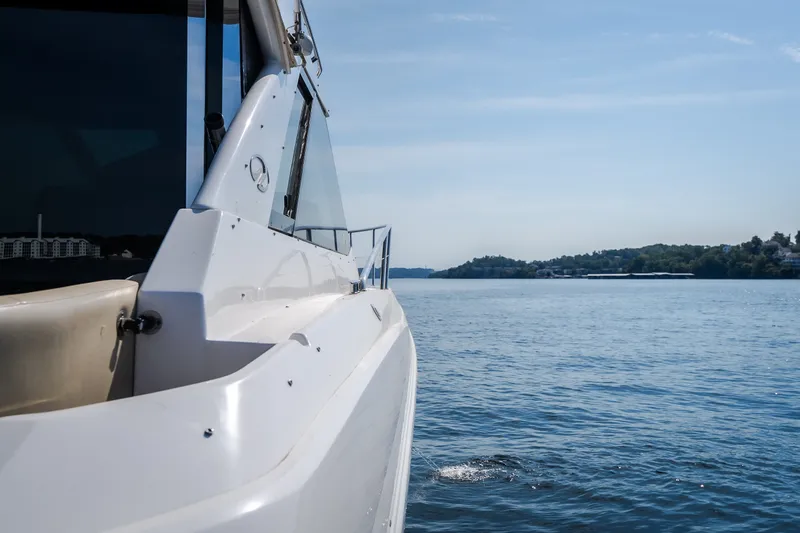 Slide: The Image of 2012 Regal 42 Sport Coupe yacht cruising on a serene lake under a clear blue sky. - 63