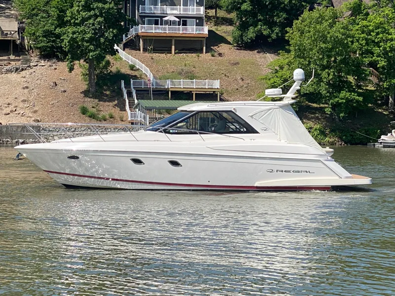 Slide: The Image of 2012 Regal 42 Sport Coupe yacht cruising on a serene lake near a wooded shoreline. - 4