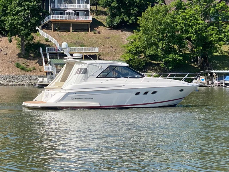 Slide: The Image of 2012 Regal 42 Sport Coupe yacht on a serene lake with lush greenery. - 5