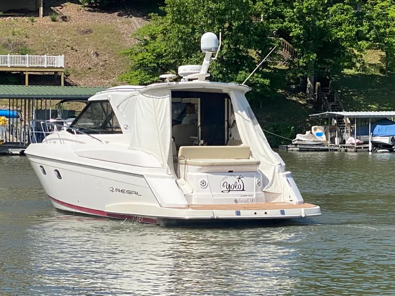 Slide: The Image of 2012 Regal 42 Sport Coupe yacht on a serene lake with lush greenery. - 7