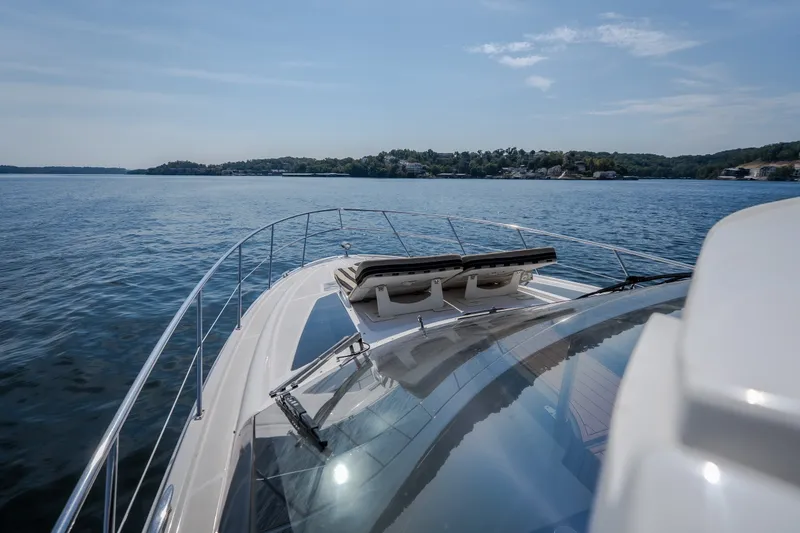 Slide: The Image of 2012 Regal 42 Sport Coupe cruising on a serene lake under a clear blue sky. - 38