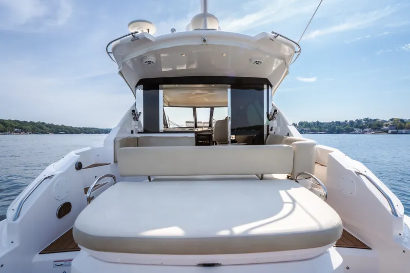 Slide: The Image of 2012 Regal 42 Sport Coupe yacht with spacious deck and seating, cruising on a serene lake. - 14