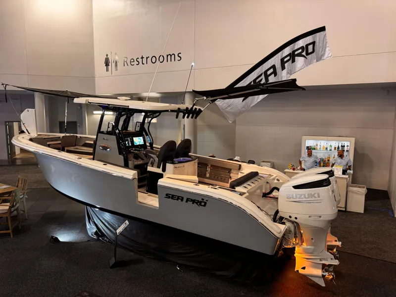 Slide: The Image of 2025 Sea Pro 292 DLX boat displayed indoors with Suzuki outboard engine. - 12