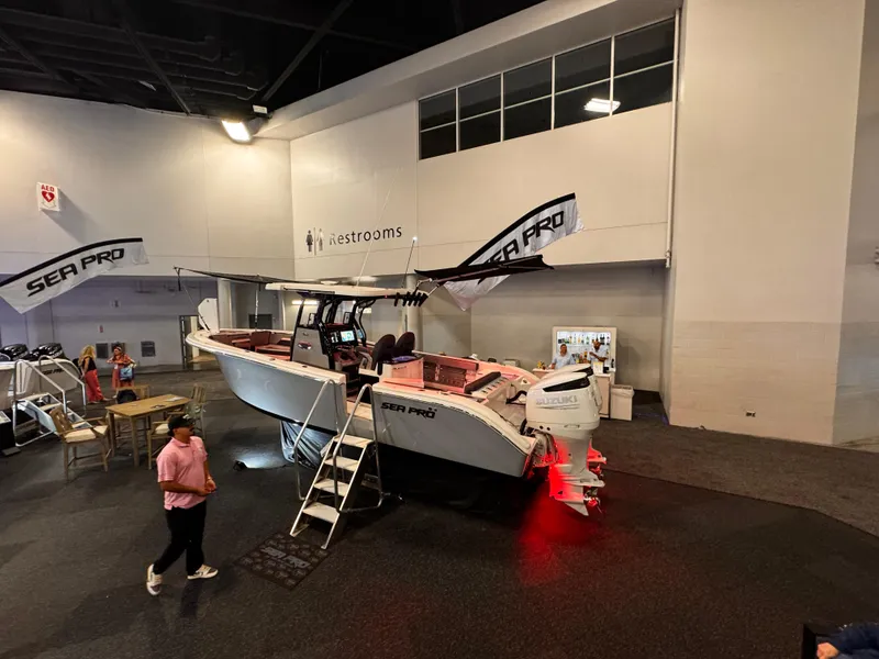 Slide: The Image of 2025 Sea Pro 292 DLX boat displayed indoors with banners and lighting. - 13