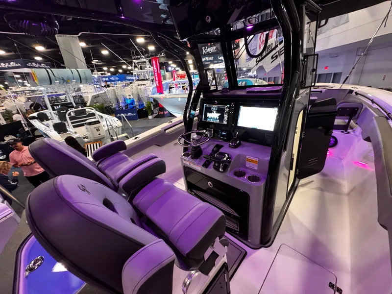 Slide: The Image of 2025 Sea Pro 292 DLX boat interior with modern dashboard and seating at a boat show. - 18