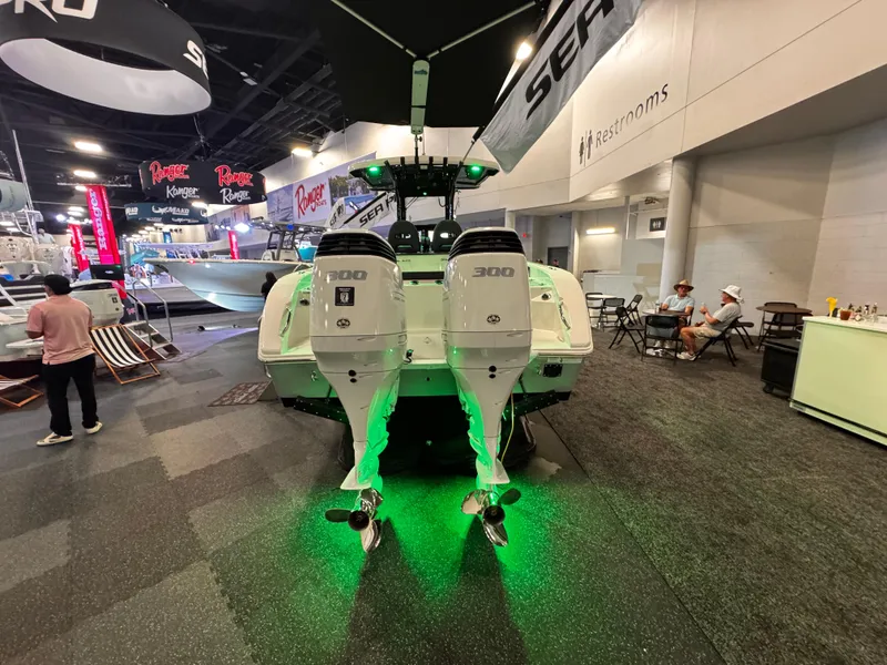 Slide: The Image of 2025 Sea Pro 292 DLX boat with dual engines, showcased indoors with green lighting. - 3