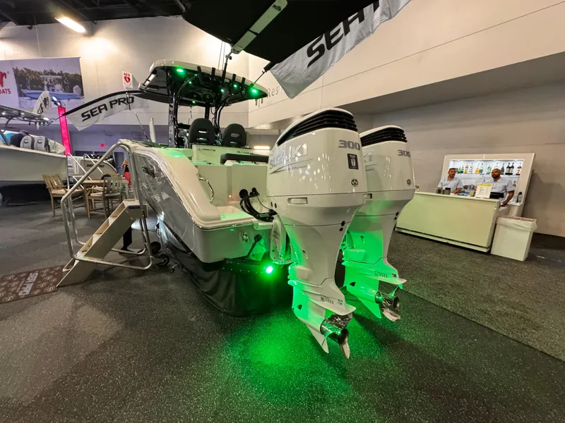 Slide: The Image of 2025 Sea Pro 292 DLX boat with dual engines and green lighting at a boat show. - 5