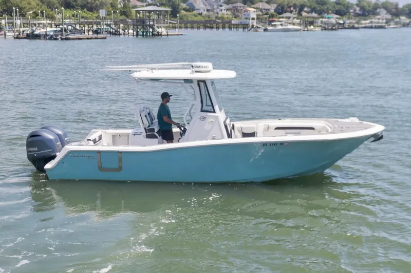 Slide: The Image of 2021 Tidewater 256 CC Adventure boat cruising on a calm waterway. - 1