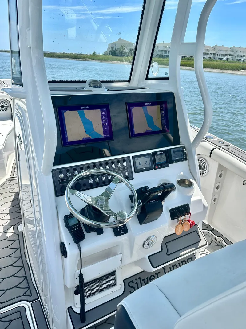 Slide: The Image of 2021 Tidewater 256 CC Adventure boat dashboard with dual navigation screens on a sunny day. - 10