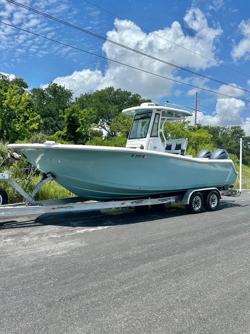 Slide: The Image of 2021 Tidewater 256 CC Adventure boat on trailer, parked on a sunny day. - 2