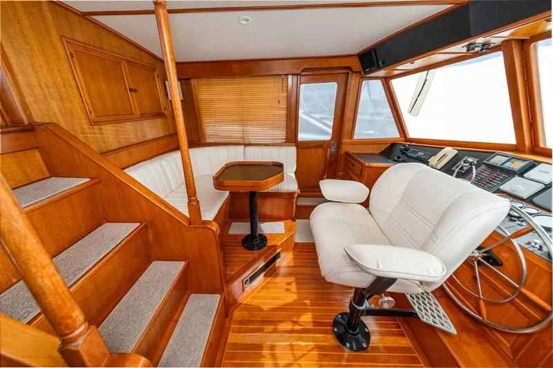 Slide: The Image of 1987 Fleming 50 Raised Pilothouse interior with wood finish, white seating, and navigation controls. - 24