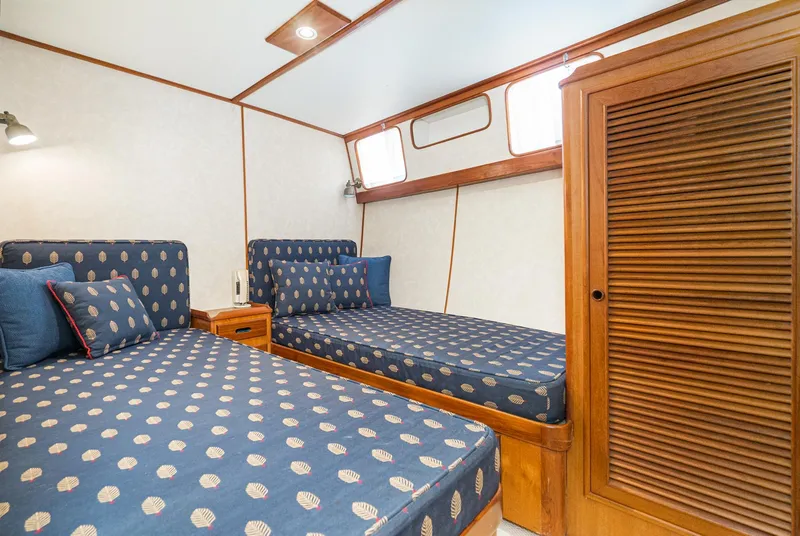 Slide: The Image of Twin beds in a 1987 Fleming 50 Raised Pilothouse cabin with nautical-themed bedding. - 31