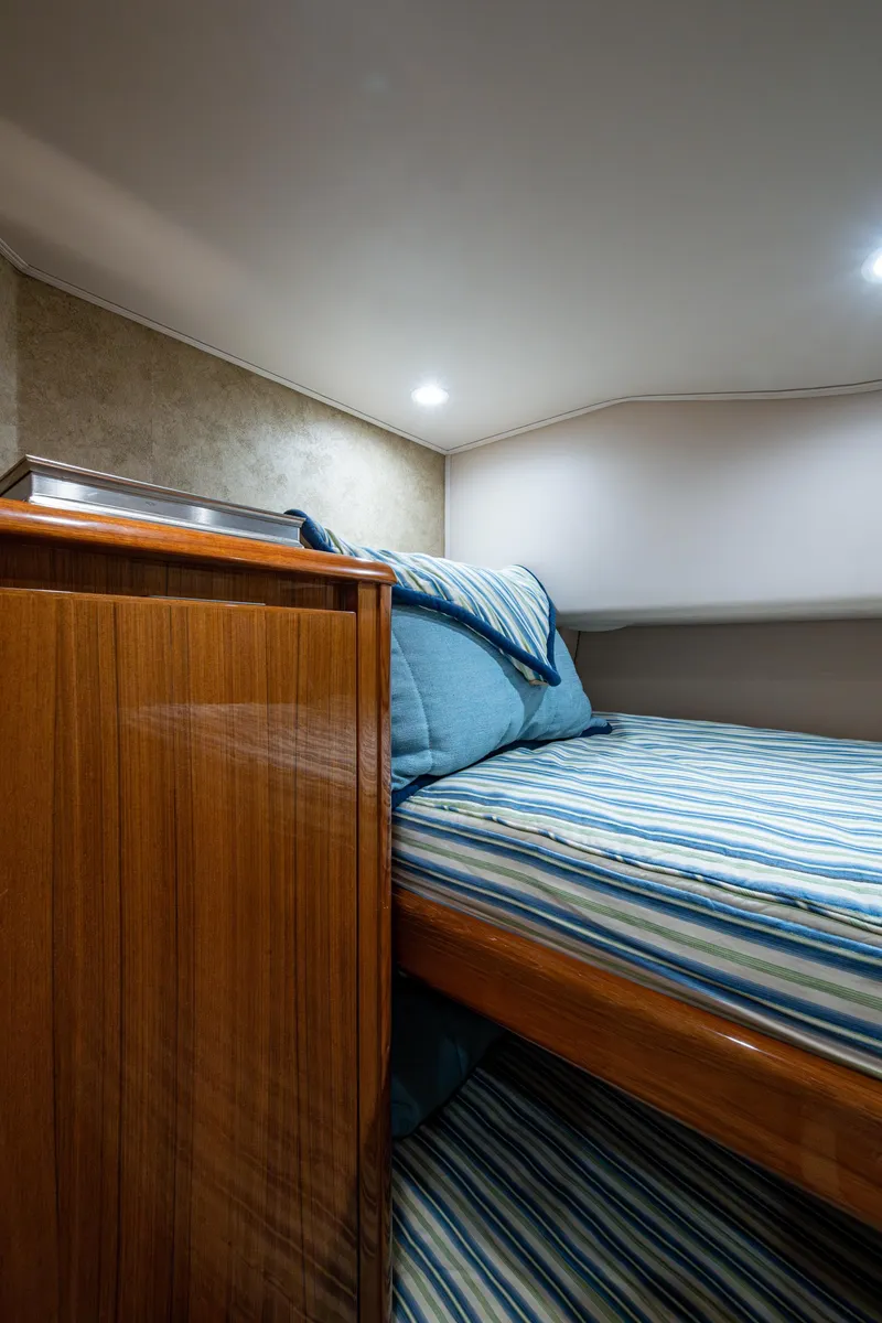 Slide: The Image of Cozy cabin interior of 2016 Viking 46 Convertible yacht with striped bedding. - 31